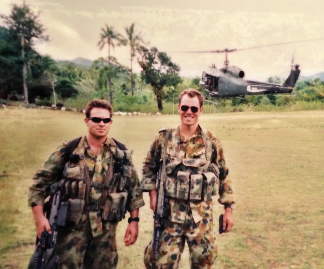 Two Australian soldiers in camouflage walking away from a Huey helicopter in East Timor, 1999